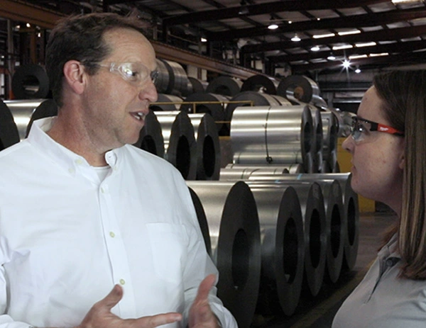 Professionals reviewing steel coils in industrial warehouse
