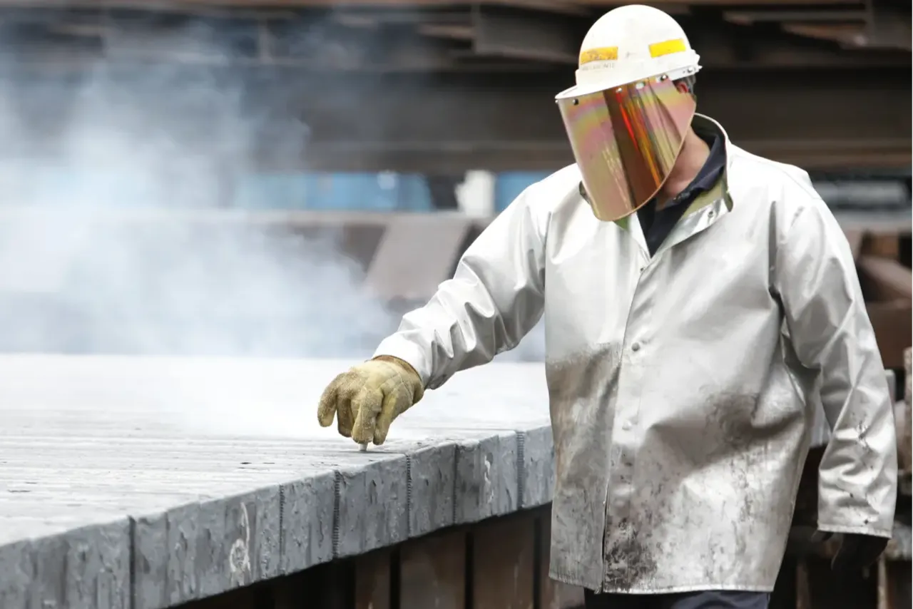 Worker handling manufacturing scrap metal during industrial recycling process