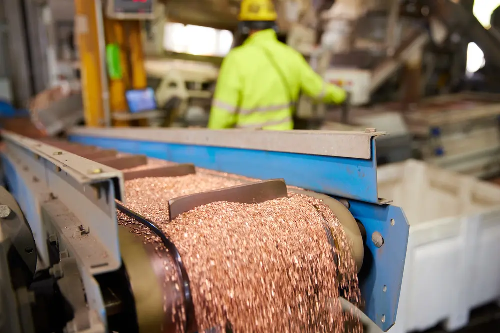 Copper scrap moving through an industrial metal processing conveyor