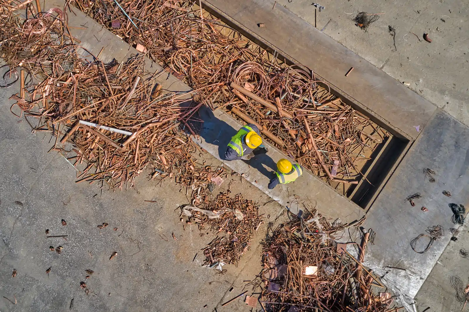 Workers processing copper scrap at recycling facility