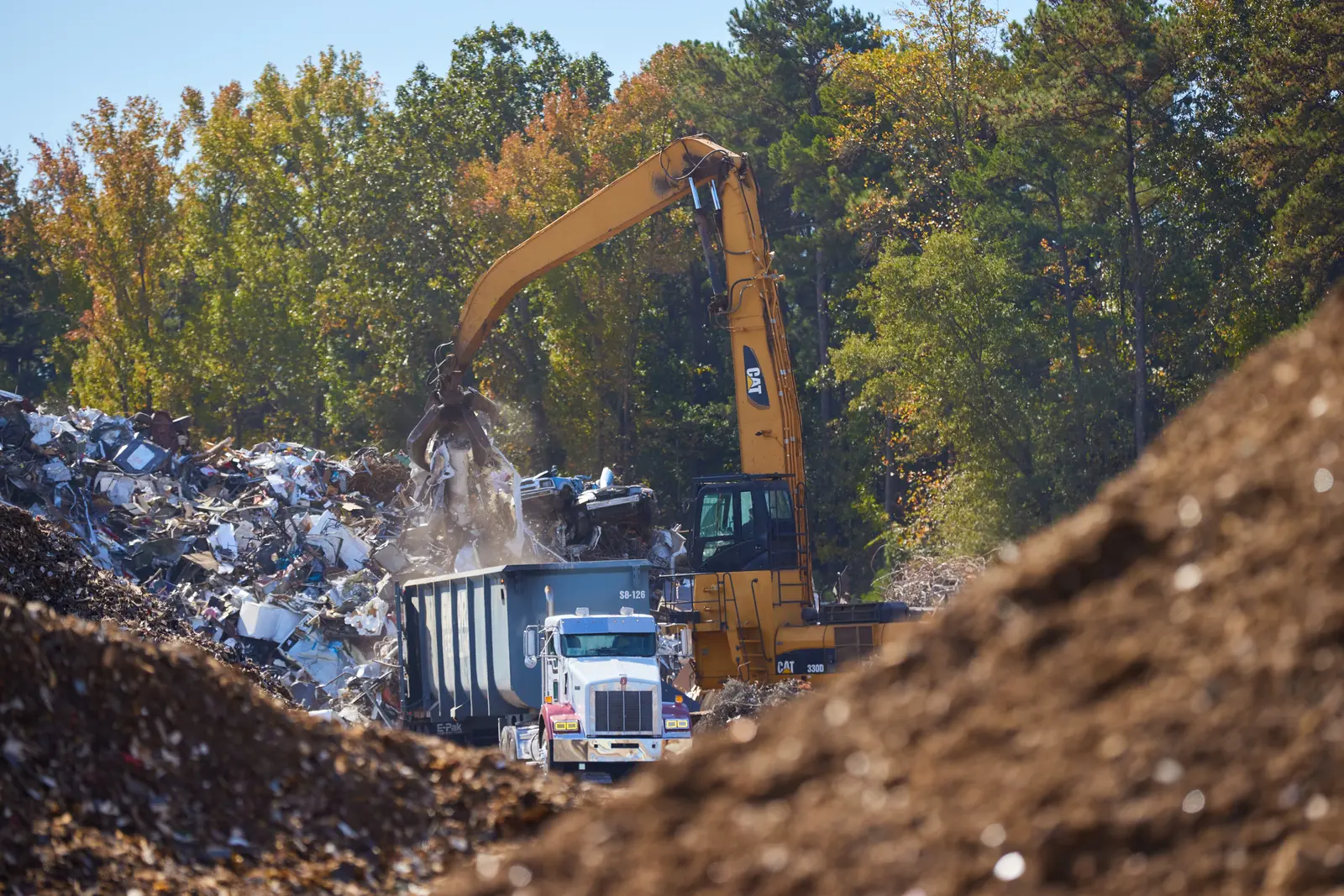 Excavator loading scrap metal for recycling and processing