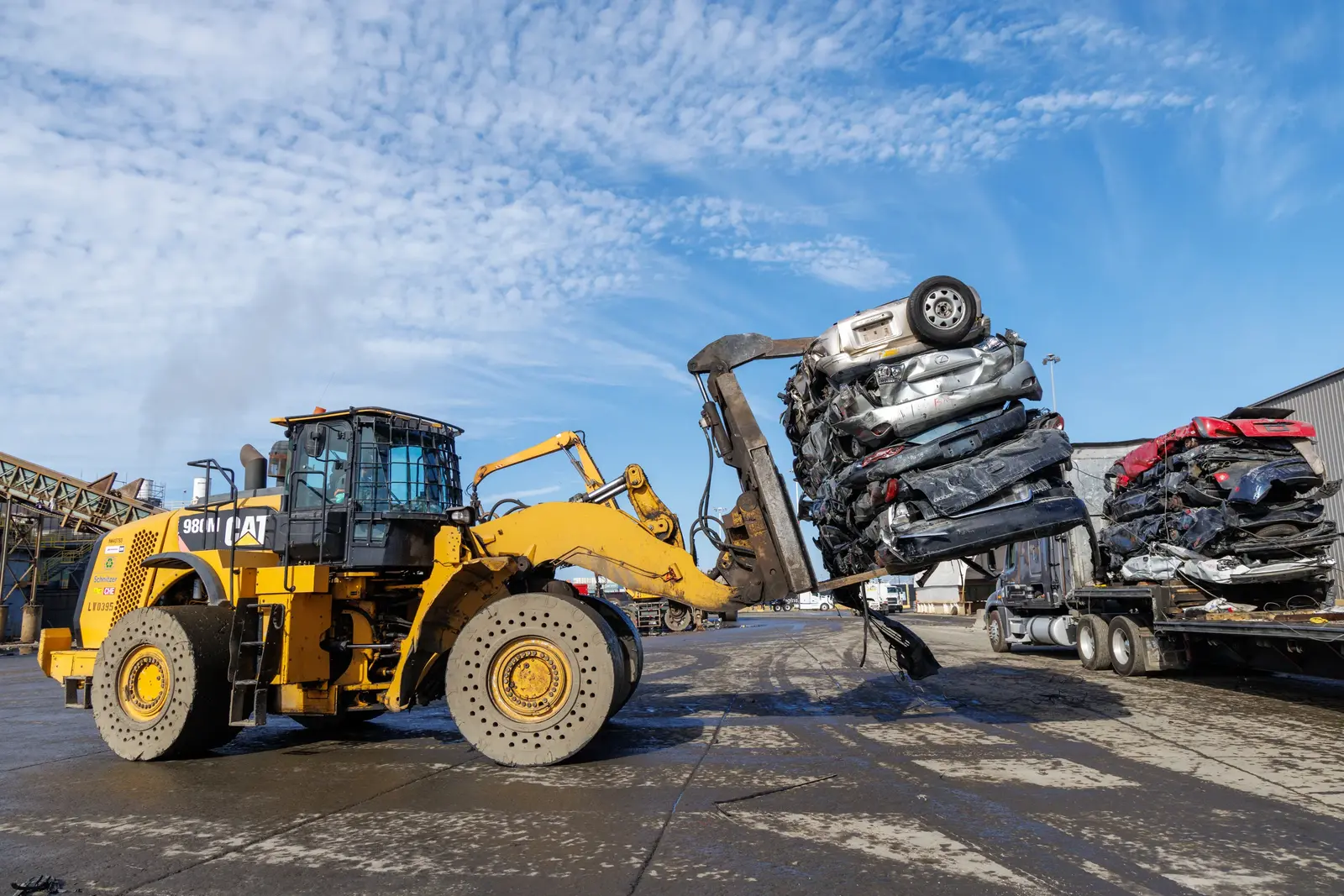 Heavy equipment loading crushed vehicles for transportation